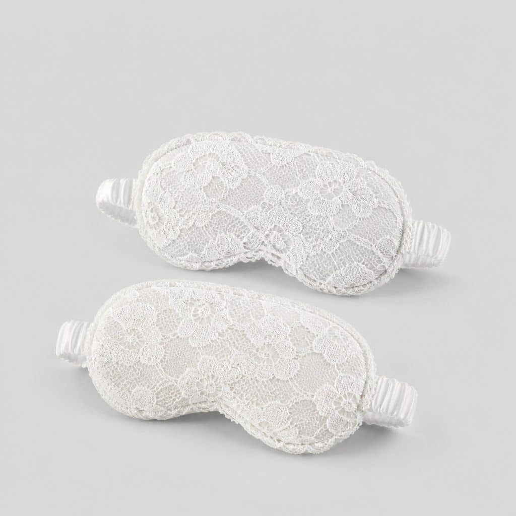 Deux masques de sommeil en dentelle posés sur un tissu clair
