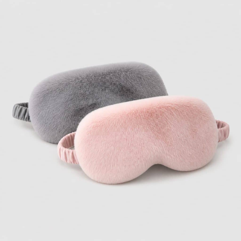 Deux masques de sommeil épais en peluche posés sur fond clair