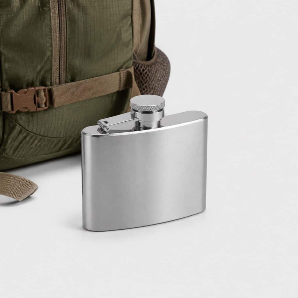 Flasque compacte en aluminium posée près d'un sac de randonnée