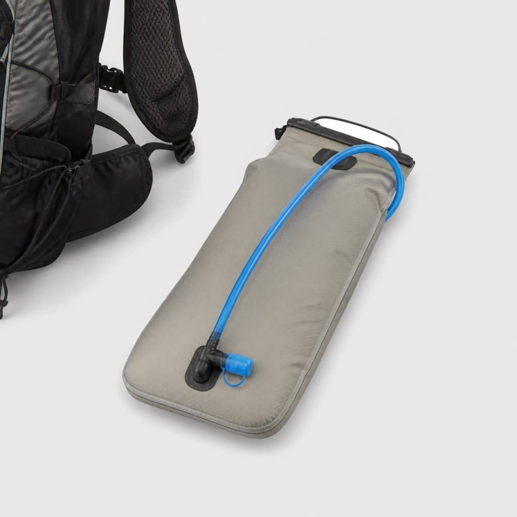 Poche à eau isotherme posée près d'un sac à dos de trail