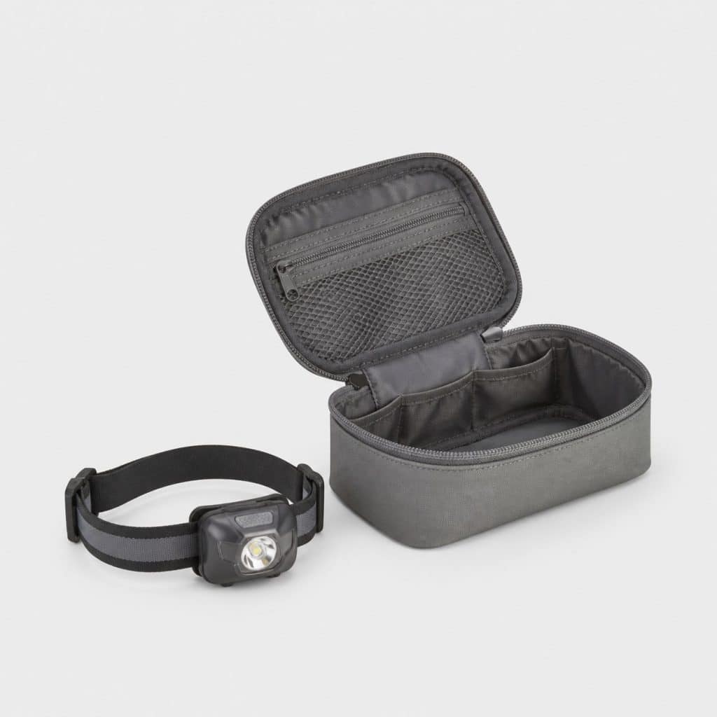 Petite lampe frontale compacte posée à côté d'une trousse de voyage